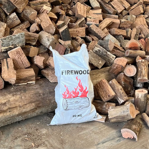 Mixed Hardwood Firewood 20kg Bag with flames design in front of stacked firewood logs