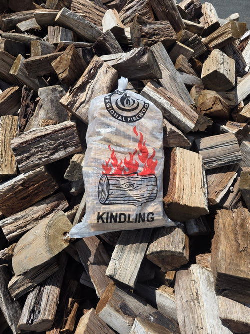 Kindling 5kg Bag Dry Pine Kindling placed on a pile of chopped wood logs with a fire logo.